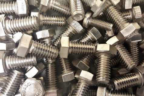 Titelbild Produktgruppe Befestigungstechnik - Viele silberfarbene Sechskantschrauben liegen dicht übereinander gestapelt.